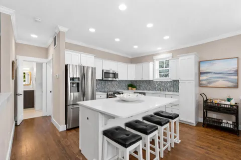 a kitchen with stainless steel appliances a dining table chairs and wooden floor