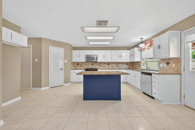 a kitchen with kitchen island granite countertop a stove a sink and a refrigerator