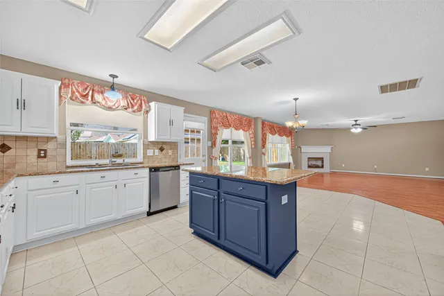 a large kitchen with kitchen island granite countertop a stove a sink and dishwasher wooden cabinets with granite countertops