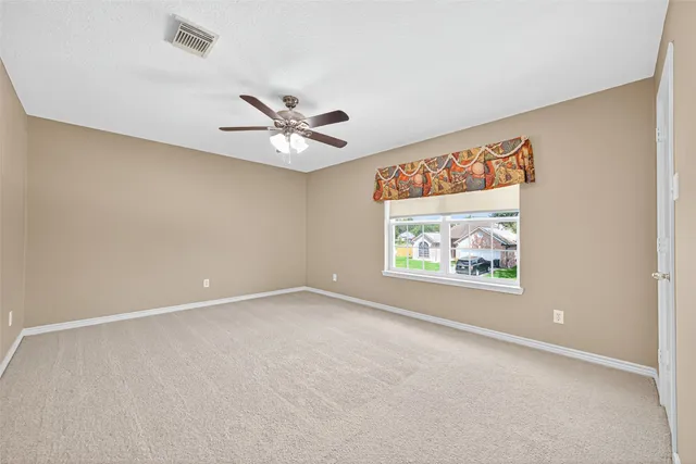 an empty room with windows and a ceiling fan