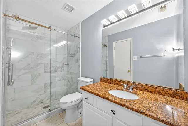 a bathroom with a granite countertop sink toilet and shower