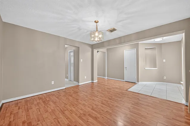 a view of an empty room with wooden floor and a bathroom