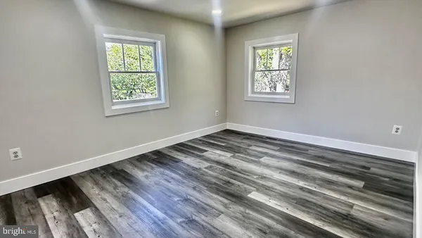 an empty room with wooden floor closet and windows