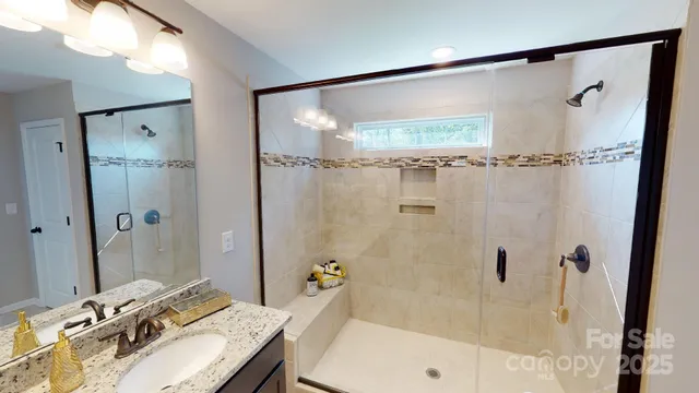 a bathroom with a granite countertop shower sink and mirror