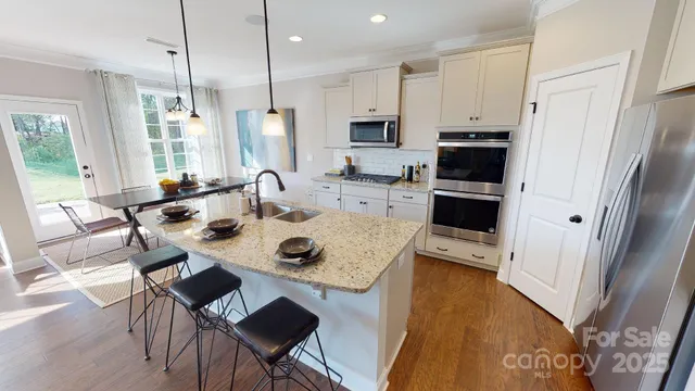a kitchen with stainless steel appliances a dining table a stove a refrigerator and cabinets
