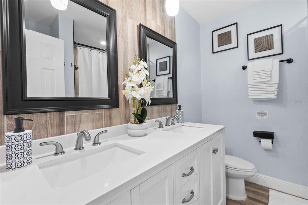 3708 North 56th Street Tampa, FL 33619 - Photo 16 of 22 a bathroom with double vanity sinks a toilet a mirror and shower