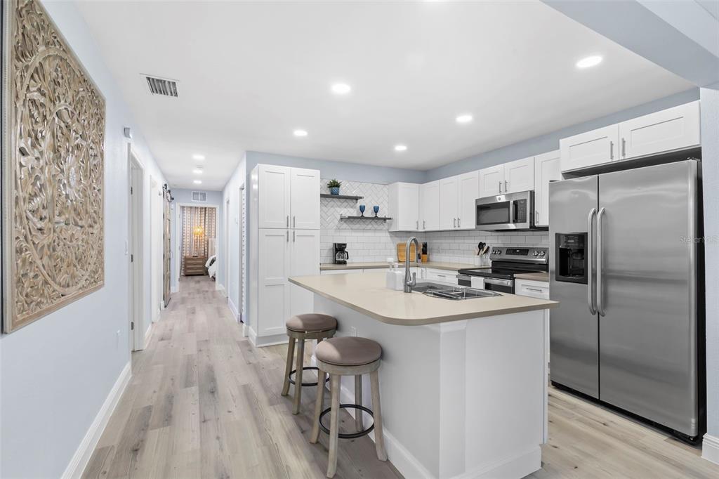 3708 North 56th Street Tampa, FL 33619 - Photo 10 of 22 a kitchen with stainless steel appliances a refrigerator a sink dishwasher a stove and white cabinets with wooden floor