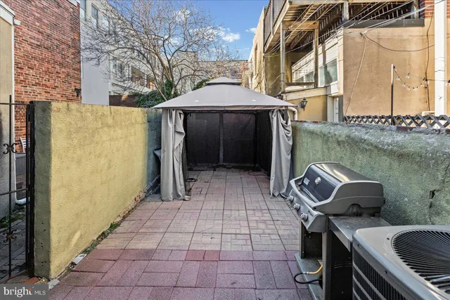 a view of a patio with table and chairs with barbeque grill and wooden fence