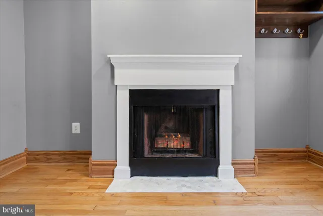 a view of an empty room with wooden floor and a fireplace