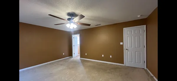 a view of an empty room with a chandelier fan