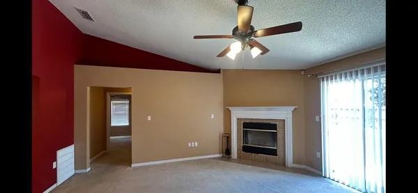 a view of an empty room with a window and fireplace
