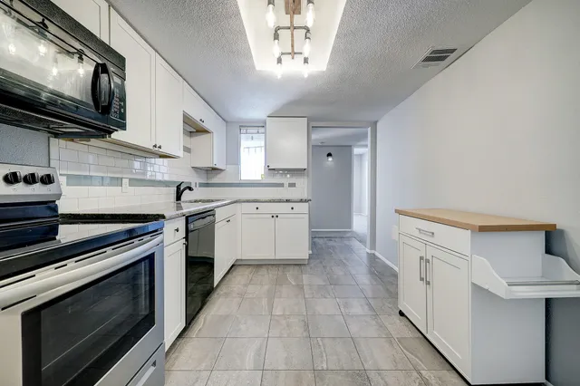 a kitchen with stainless steel appliances white cabinets and a stove top oven
