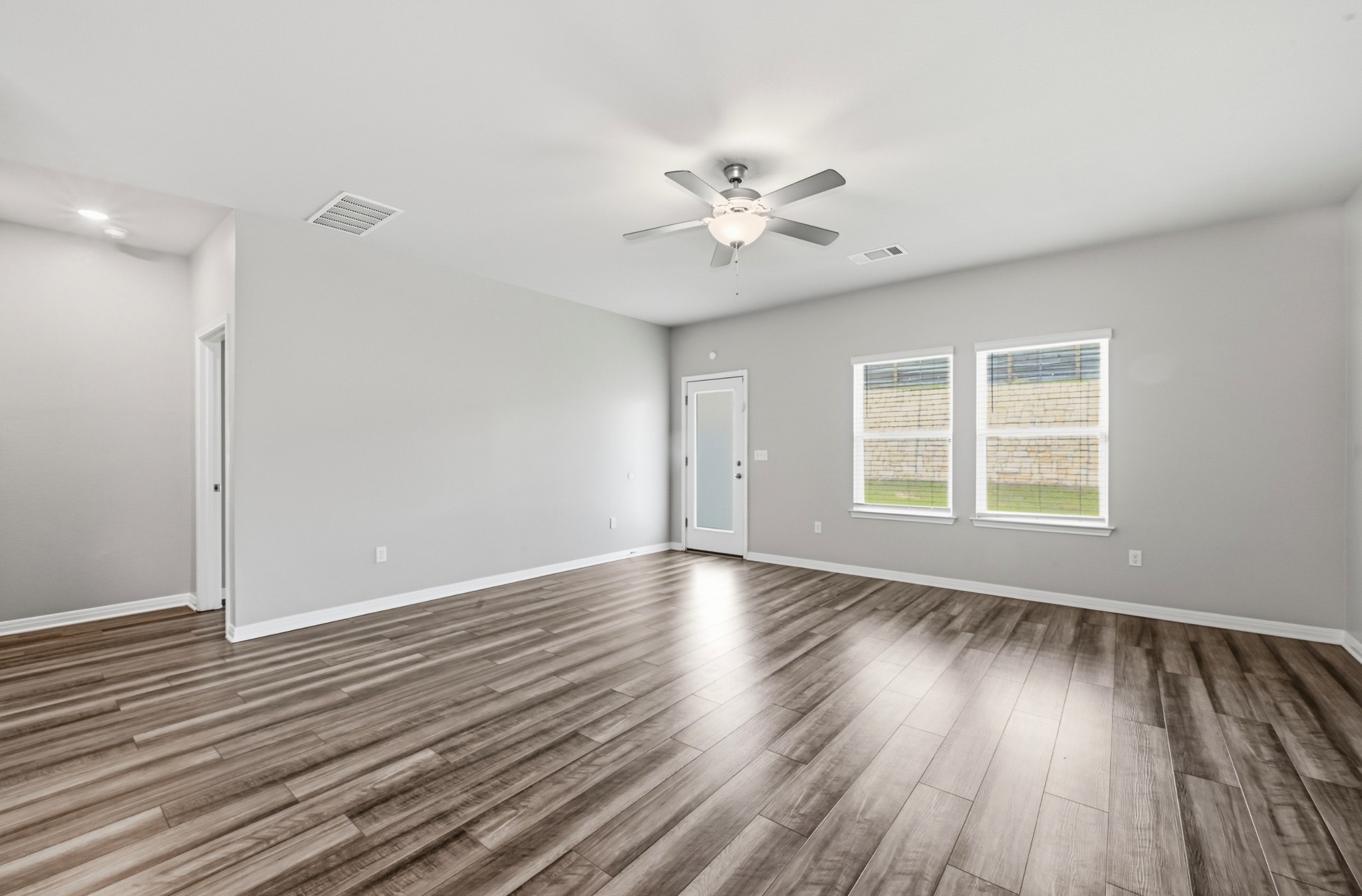 12606 Dairywork Road Buda, TX 78610 - Photo 12 of 32 a view of an empty room with wooden floor and a window