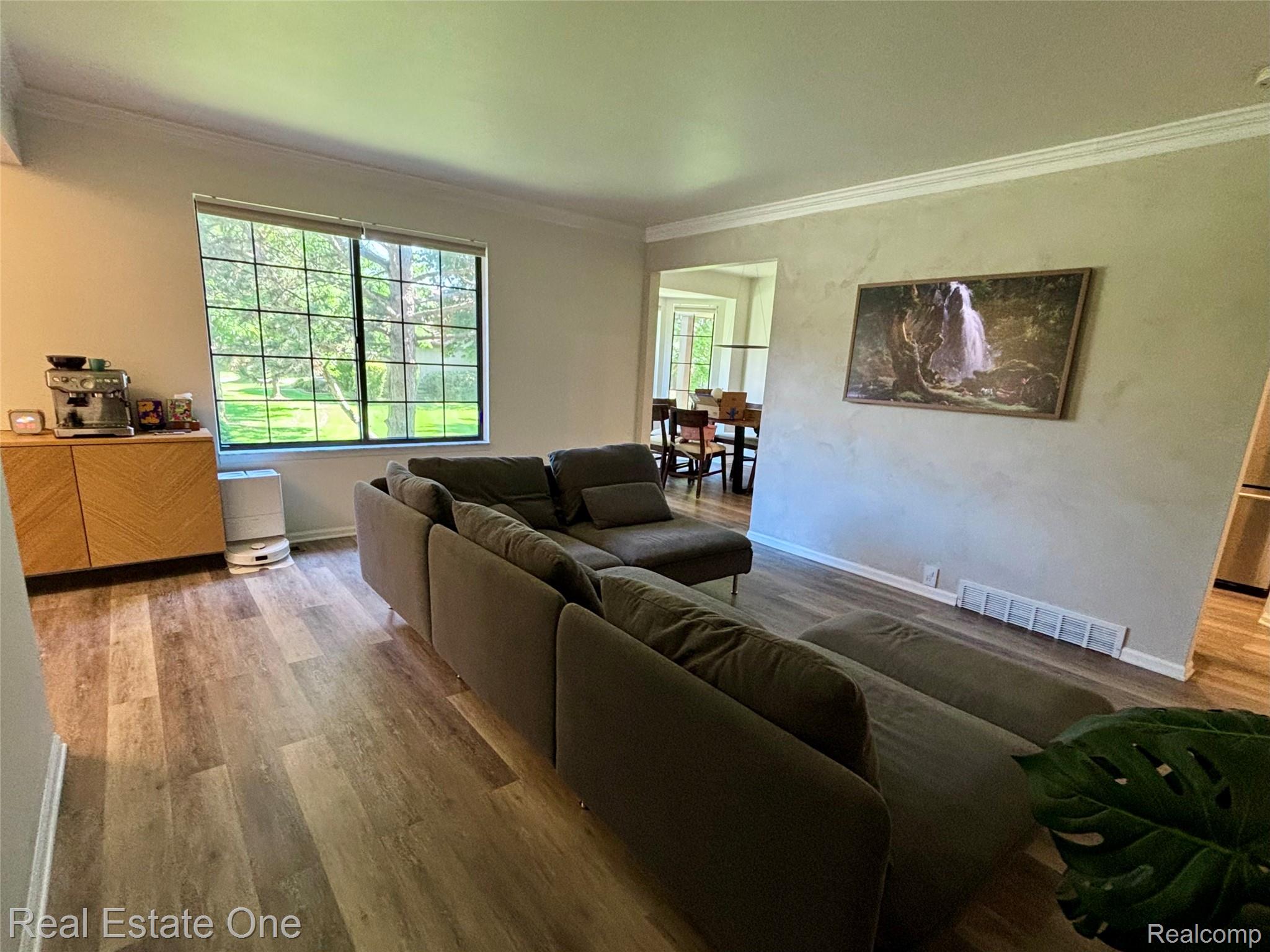 66 Meadow Wood Drive Rochester, MI 48307 - Photo 6 of 20 Spacious living area featuring wood-finish flooring, a large grid-pattern window, and crown molding