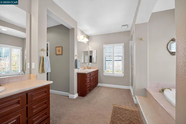 a spacious bathroom with a tub sink and mirror
