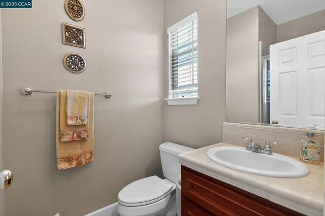 a bathroom with a granite countertop toilet sink and mirror