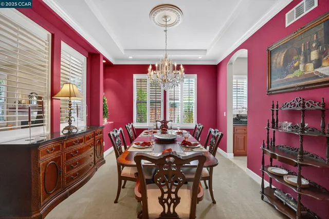 a view of a dining room with furniture a chandelier and large windows