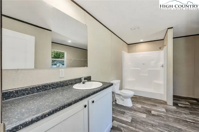 a bathroom with a granite countertop sink a toilet a mirror and shower