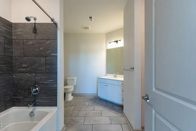 a bathroom with a granite countertop sink a toilet and shower