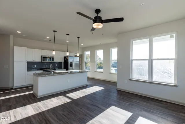 a large white kitchen with a large window a sink and stainless steel appliances
