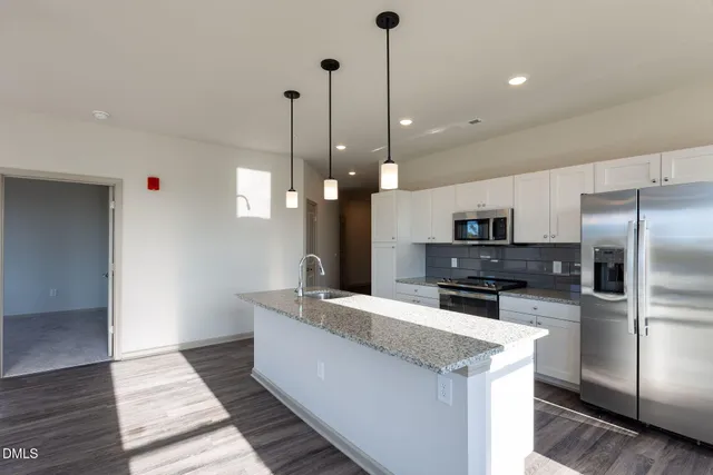 a large kitchen with kitchen island a large counter top a sink stainless steel appliances and cabinets