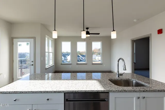 a kitchen with kitchen island granite countertop a sink a counter top space and living room view