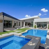 a view of swimming pool with lawn chairs and plants