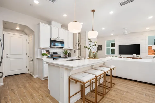 a kitchen with stainless steel appliances granite countertop a stove top oven a sink dishwasher a dining table and chairs with wooden floor