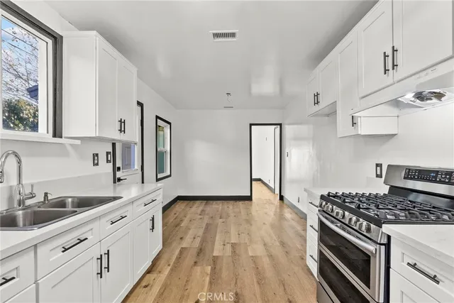 a kitchen with granite countertop a sink cabinets stainless steel appliances and a window