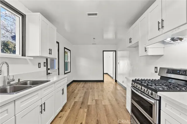 a kitchen with granite countertop a sink cabinets stainless steel appliances and a window