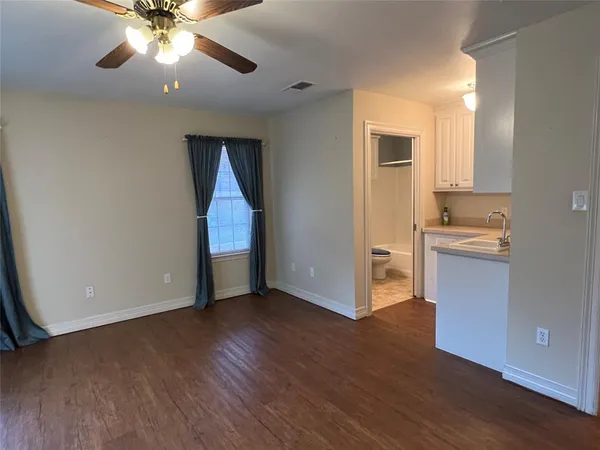 a view of an empty room with window and wooden floor