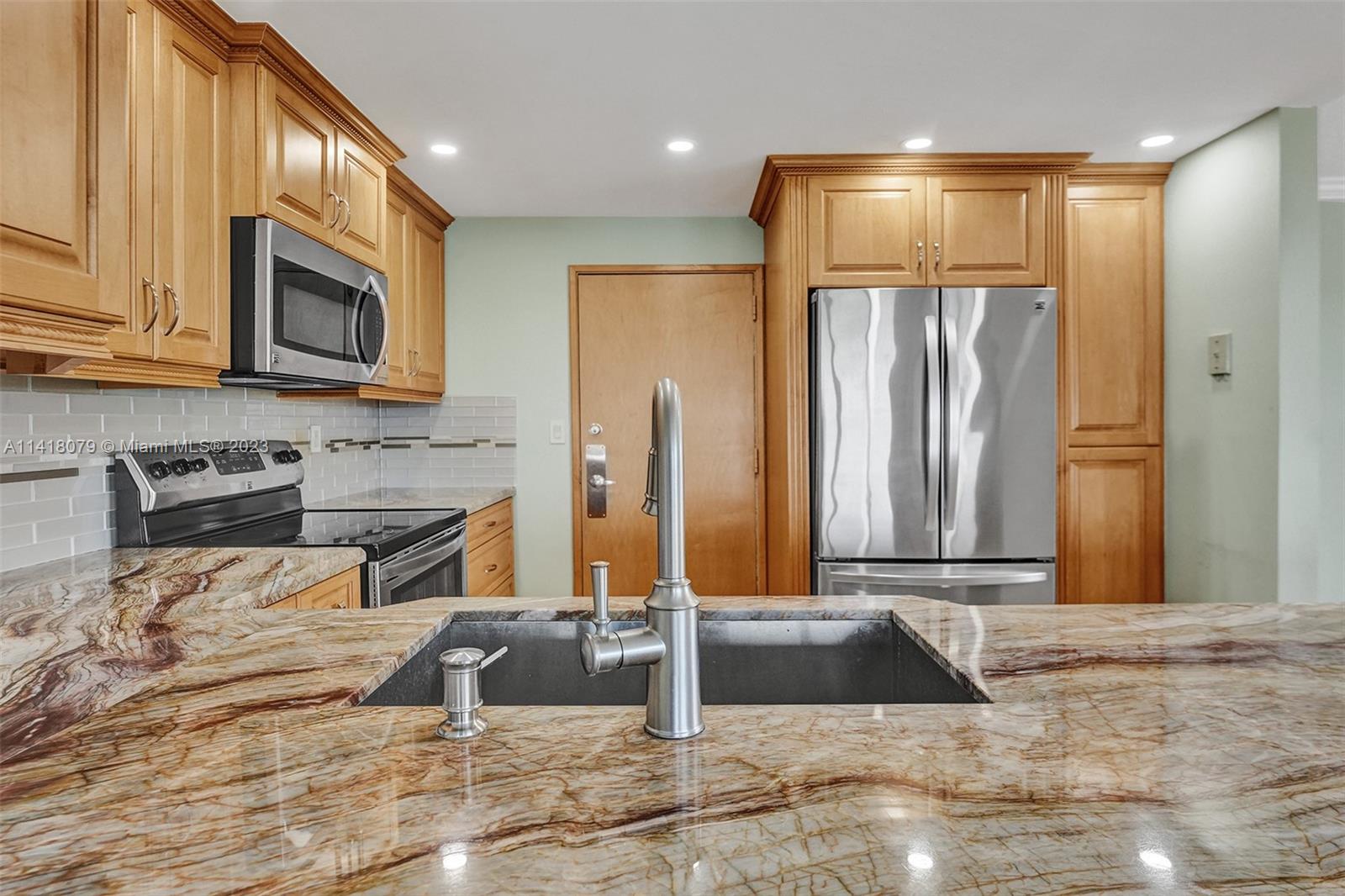 10777 West Sample Road, Unit 614 Coral Springs, FL 33065 - Photo 18 of 40 a kitchen with stainless steel appliances granite countertop a stove a sink and a microwave