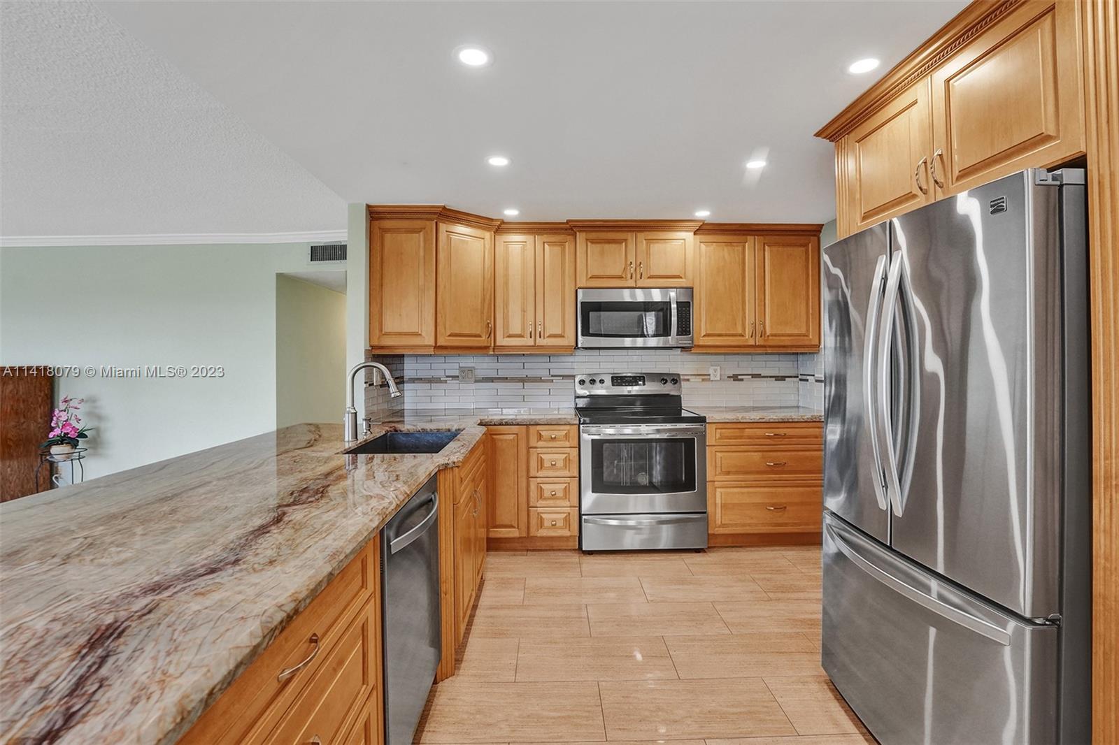 10777 West Sample Road, Unit 614 Coral Springs, FL 33065 - Photo 19 of 40 a kitchen with stainless steel appliances granite countertop a refrigerator sink and stove