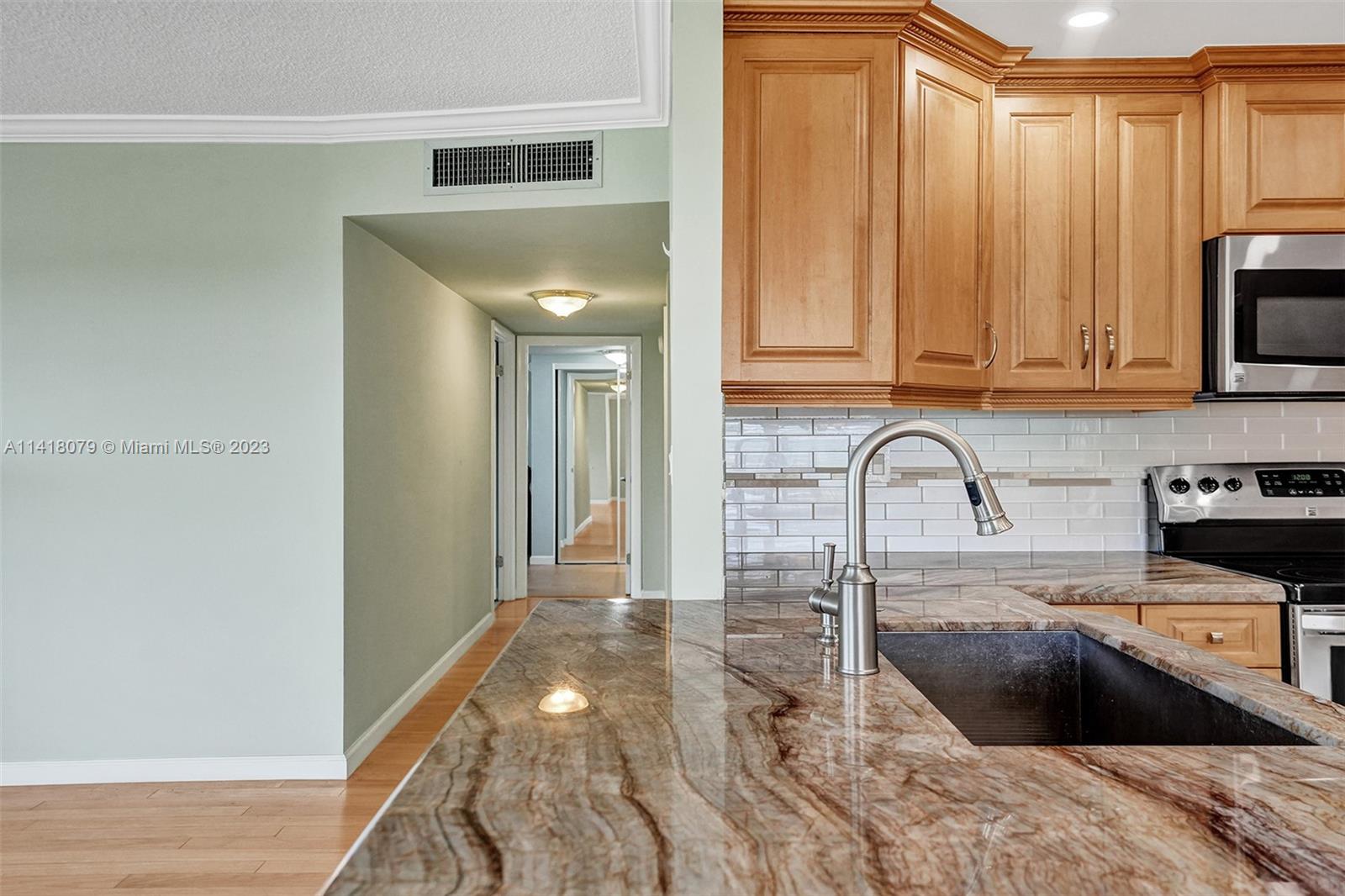 10777 West Sample Road, Unit 614 Coral Springs, FL 33065 - Photo 21 of 40 a kitchen with granite countertop a stove a sink and a microwave