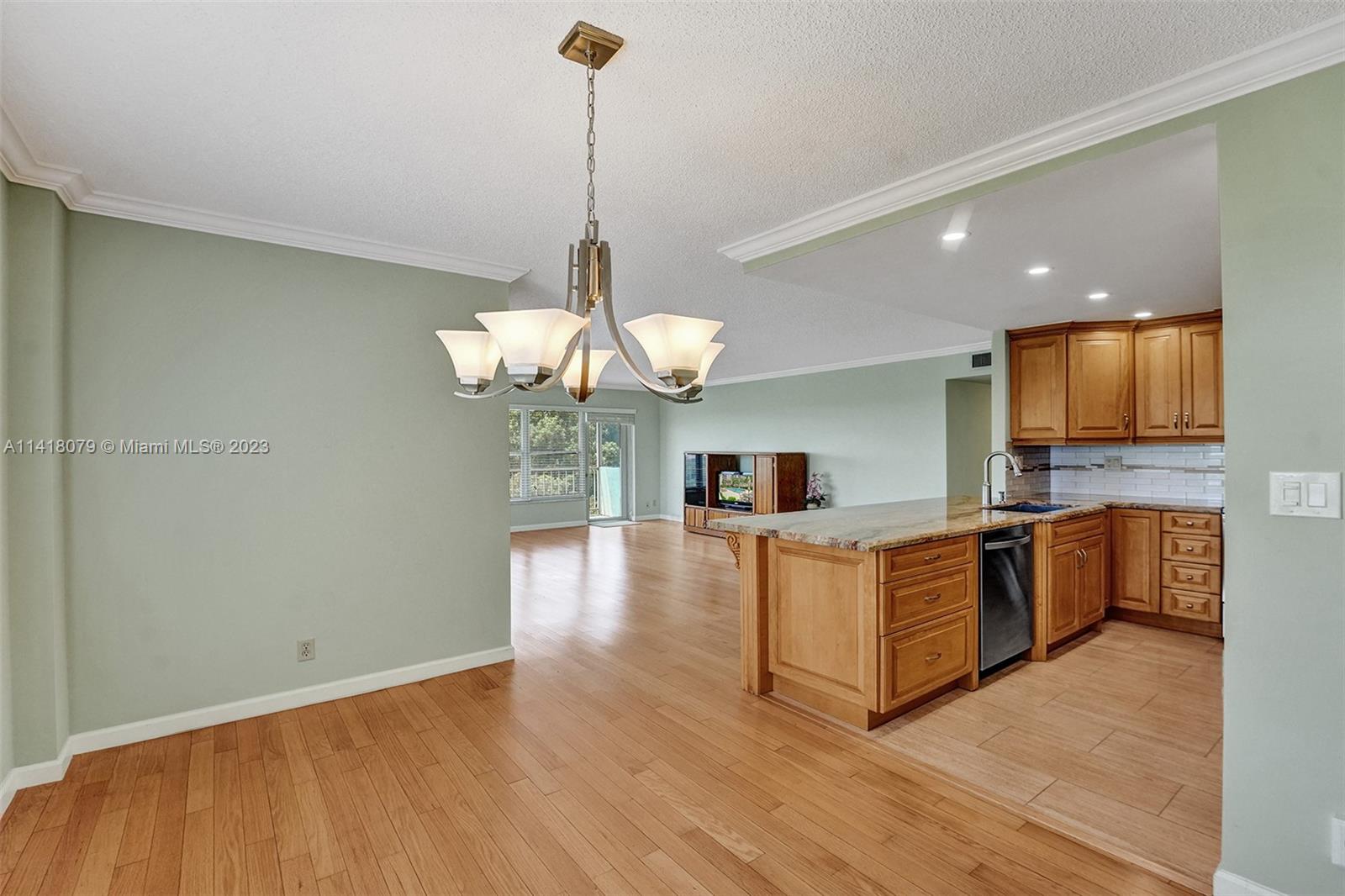 10777 West Sample Road, Unit 614 Coral Springs, FL 33065 - Photo 23 of 40 a view of a kitchen with granite countertop stainless steel appliances and wooden floor