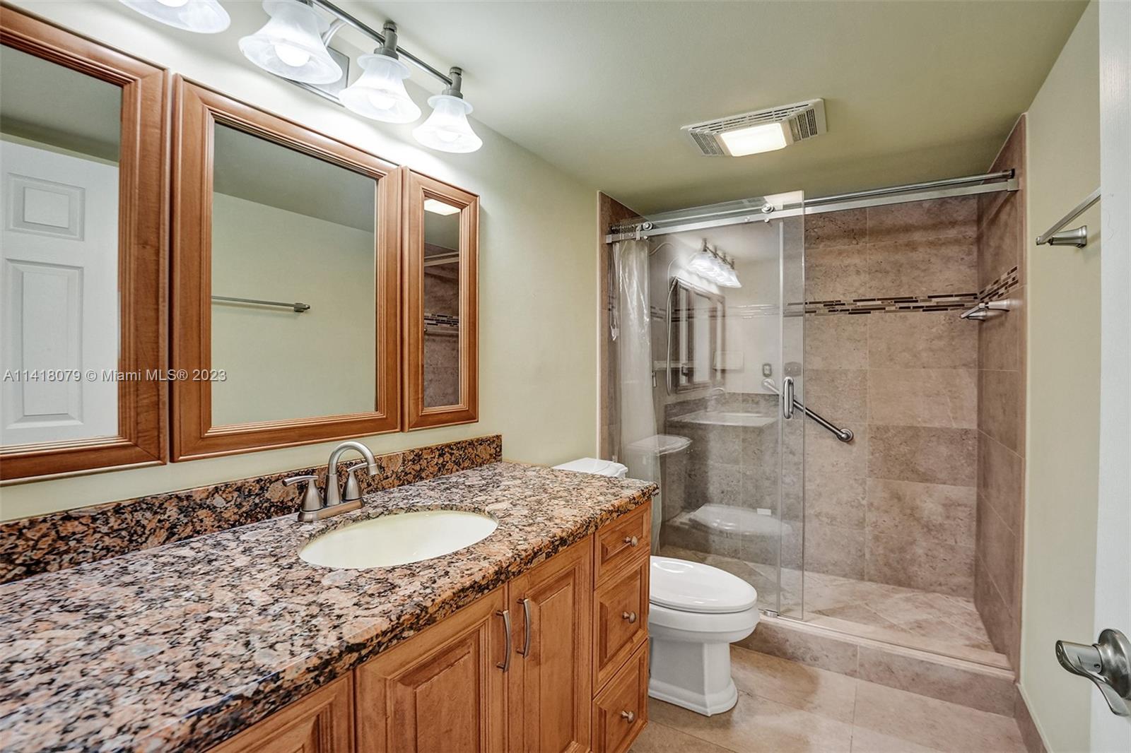 10777 West Sample Road, Unit 614 Coral Springs, FL 33065 - Photo 32 of 40 a bathroom with a granite countertop sink toilet a mirror and shower