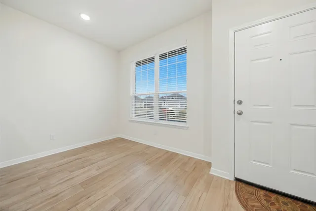 a view of an empty room with wooden floor and a window