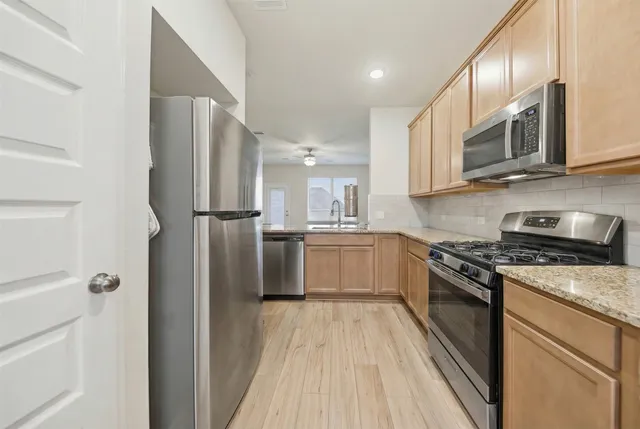 a kitchen with stainless steel appliances granite countertop a refrigerator a stove and a sink