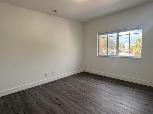 an empty room with wooden floor and windows