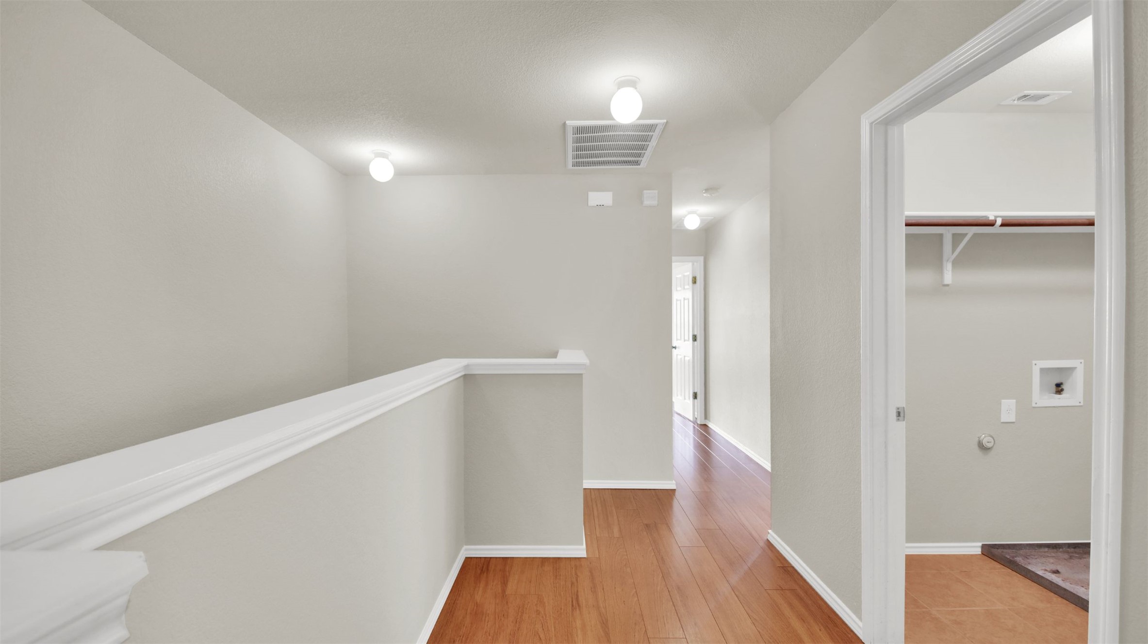 73 Verde Ranch Loop Leander, TX 78641 - Photo 28 of 29 Corridor with baseboards, visible vents, light wood-style flooring, and an upstairs landing