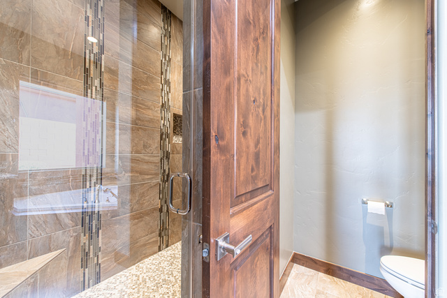 322 340 E Street Ivins, UT 84738 - Photo 29 of 61 Glass-enclosed shower featuring large format wall tiles, decorative mosaic tile accents, and a pebble stone floor