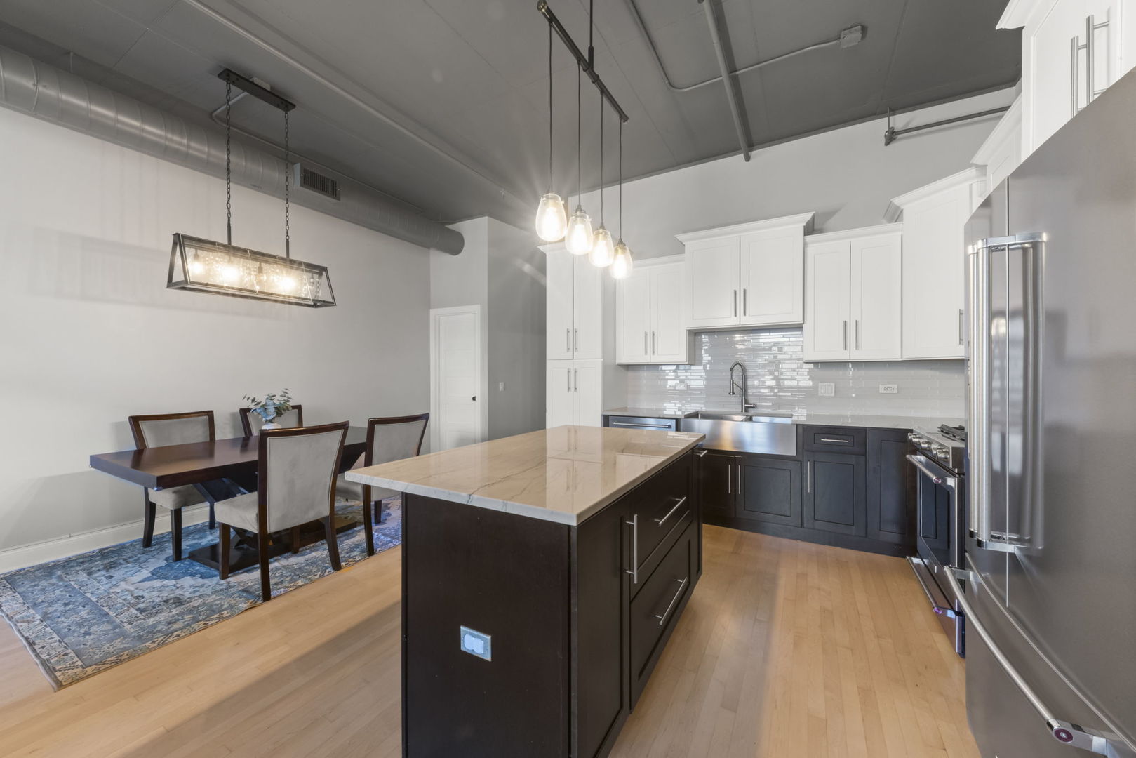 1301 West Madison Street, Unit 305 Chicago, IL 60607 - Photo 6 of 22 a kitchen with a stove a refrigerator a sink dishwasher with a dining table and chairs