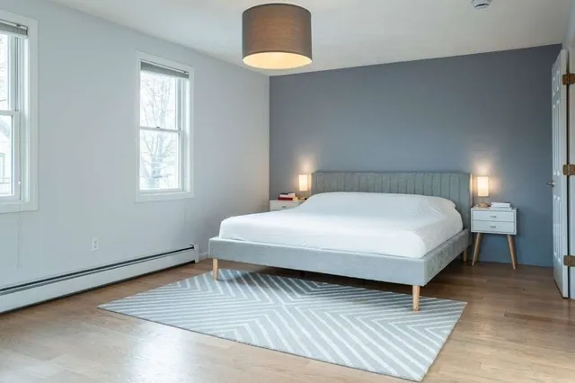a view of an empty room with wooden floor and a bench