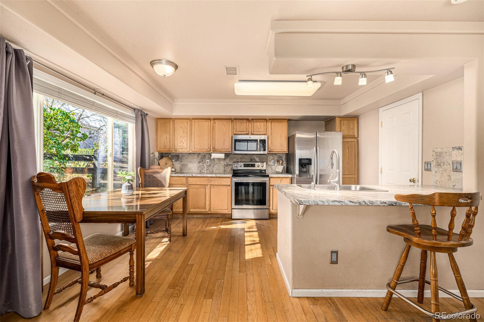 21300 East 42nd Avenue Denver, CO 80249 - Photo 16 of 48 a kitchen with stainless steel appliances granite countertop a stove top oven a sink dishwasher a dining table and chairs with wooden floor