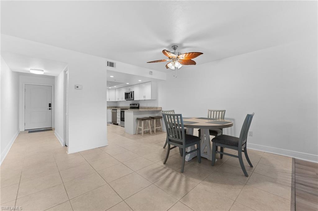 14053 Northumberland Drive Southwest, Unit 105 Fort Myers, FL 33908 - Photo 15 of 38 a view of a dining room and kitchen with furniture and a chandelier