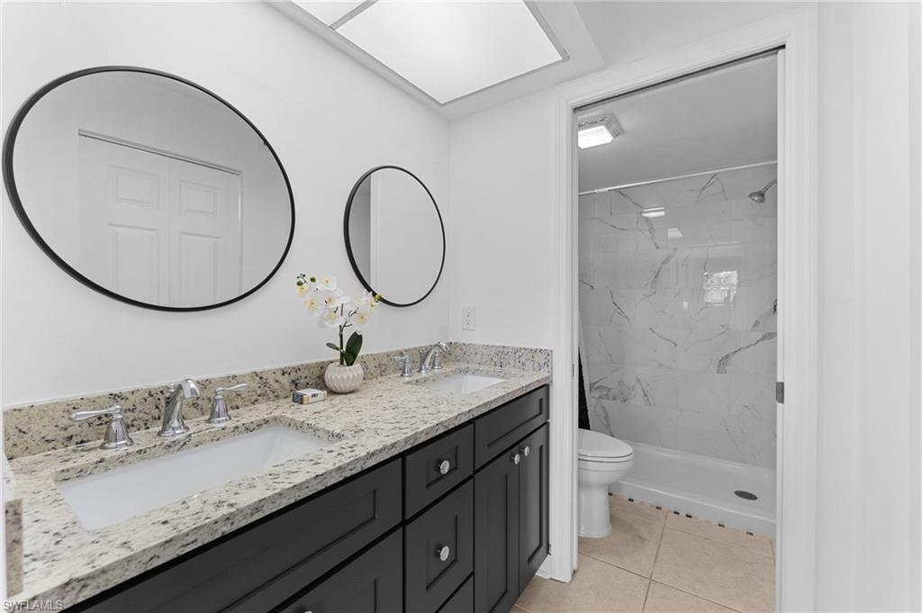 14053 Northumberland Drive Southwest, Unit 105 Fort Myers, FL 33908 - Photo 18 of 38 a bathroom with a granite countertop toilet a sink and a mirror