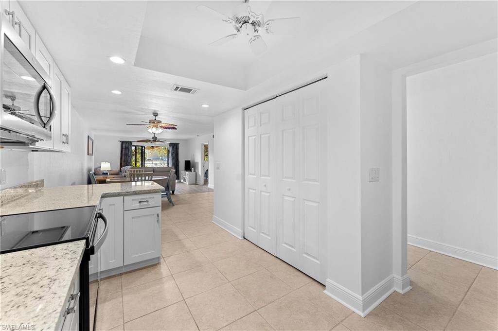 14053 Northumberland Drive Southwest, Unit 105 Fort Myers, FL 33908 - Photo 8 of 38 a large white kitchen with a sink and dishwasher a stove top oven with wooden floor