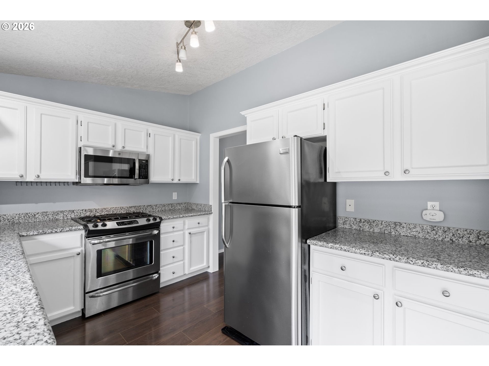 895 Southwest 166th Avenue Beaverton, OR 97006 - Photo 8 of 36 a kitchen with stainless steel appliances granite countertop white cabinets a refrigerator a stove a sink and a microwave