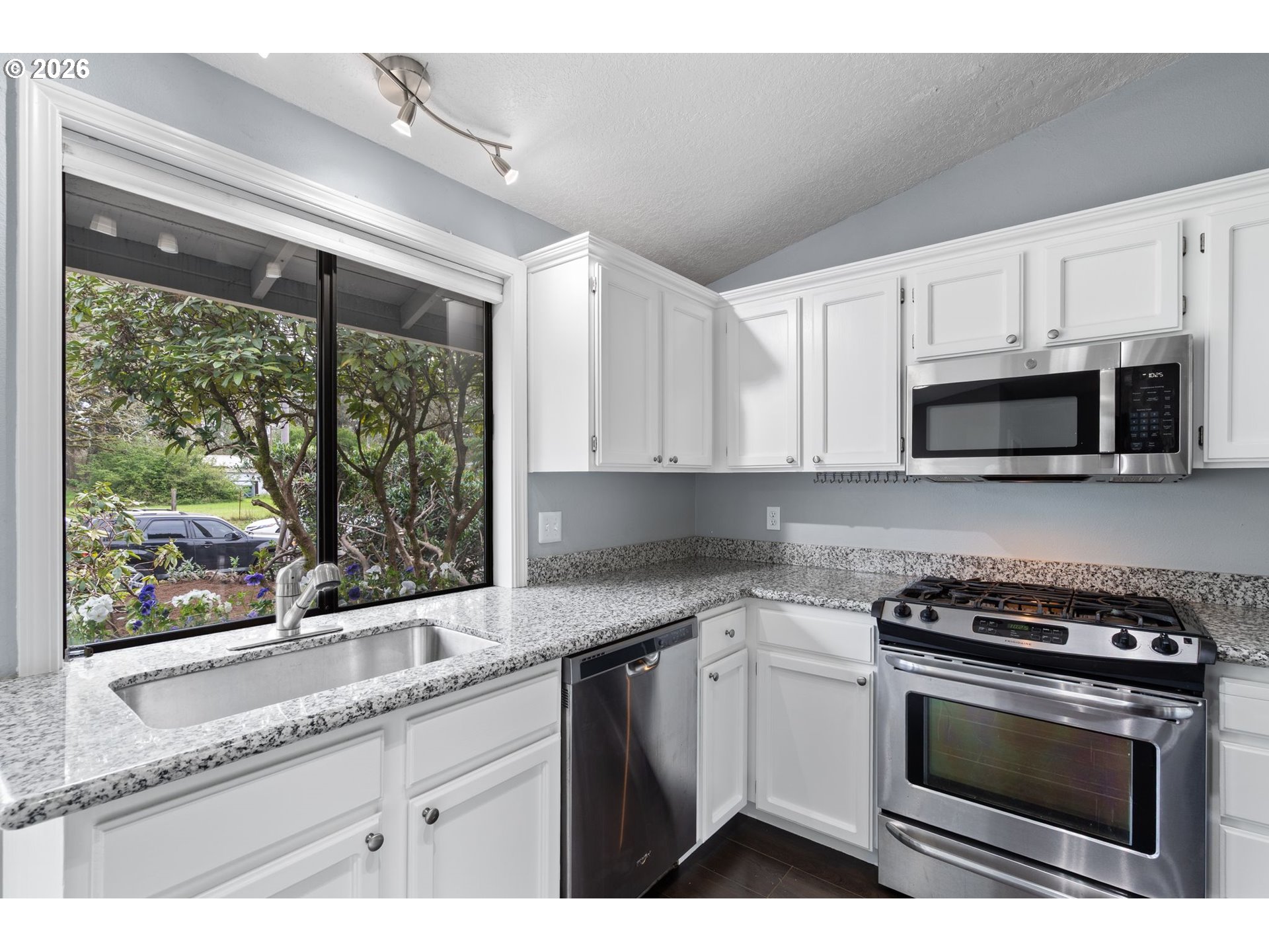 895 Southwest 166th Avenue Beaverton, OR 97006 - Photo 9 of 36 a kitchen with granite countertop a stove a sink and a microwave