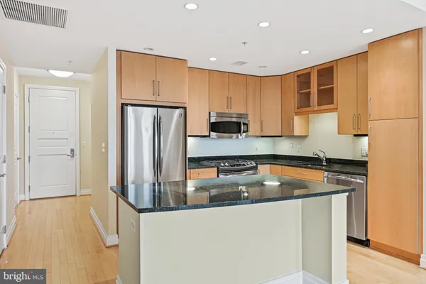 a kitchen with stainless steel appliances granite countertop a refrigerator a stove and a sink with wooden floor